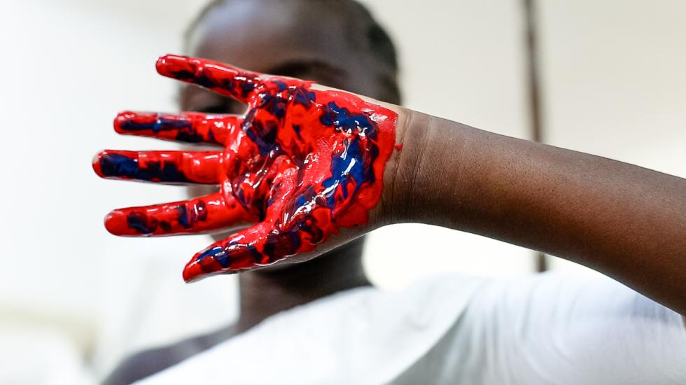 A child holds up a hand with paint during and activity at the Kabinda Central Hospital paediatric ward. 